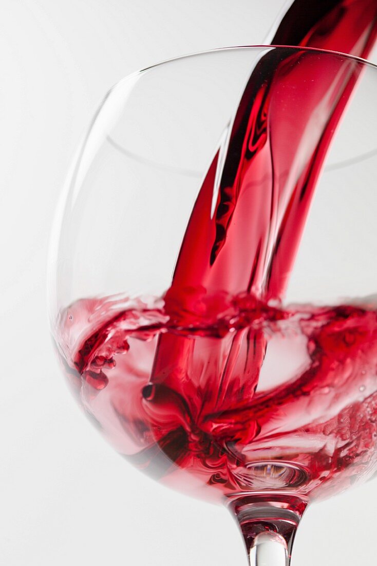 Rotwein fliesst in Weinglas
