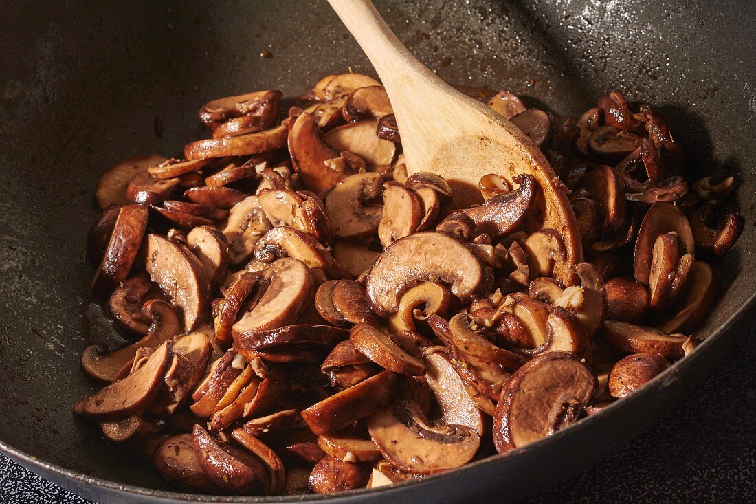 In Olivenöl gebratene braune Champignons mit gehacktem Knoblauch im Wok