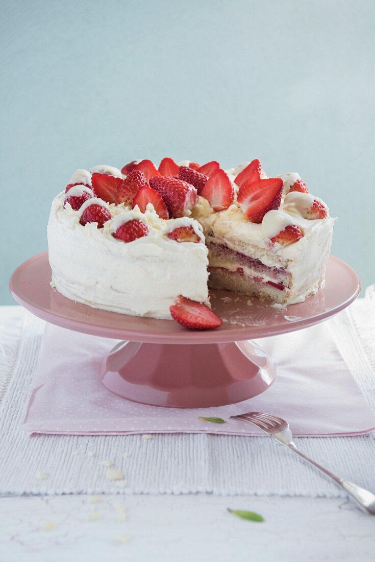 weiße-Schokolade-Erdbeer-Kuchen auf Tortenständer, angeschnitten