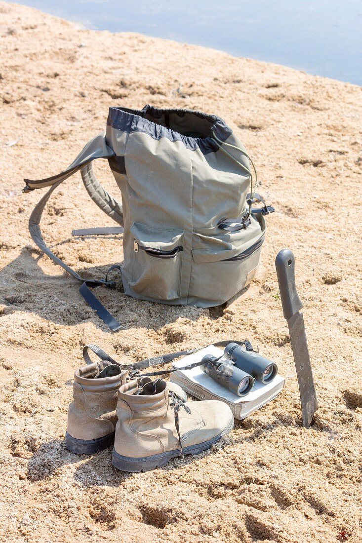 A rucksack and shoes in the sand by a watering hole, Zambia, Africa