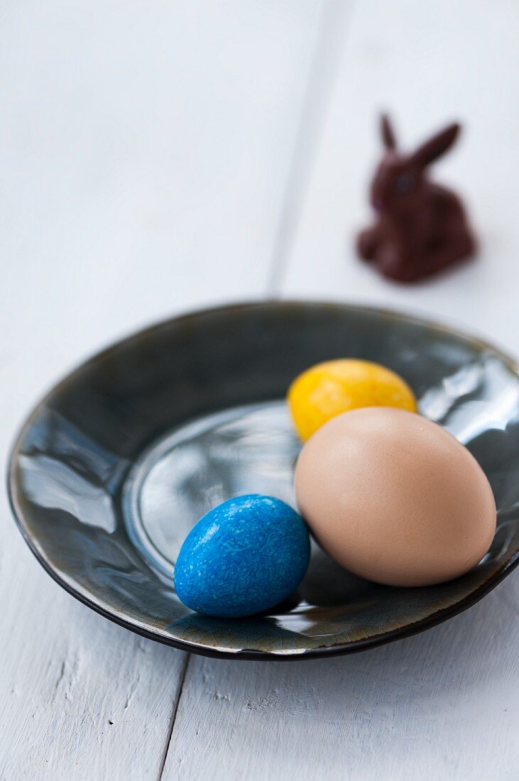 Bunte Eier auf Teller vor Schokoladenosterhasen