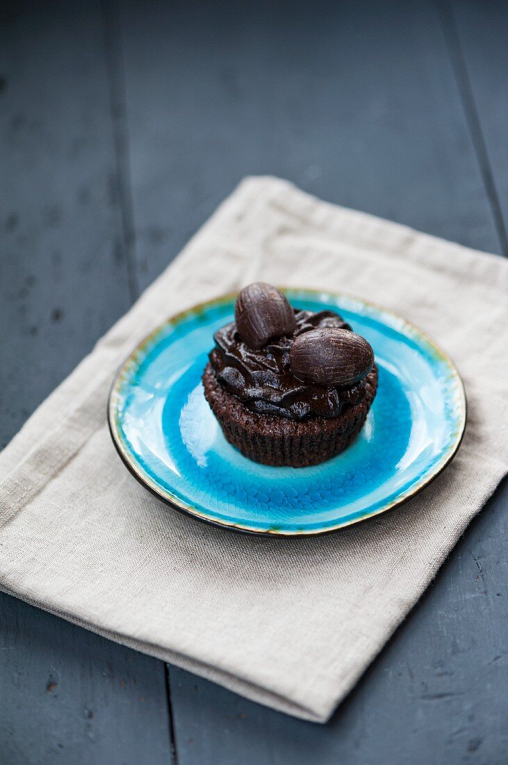 A chocolate cupcake with chocolate frosting and chocolate Easter eggs