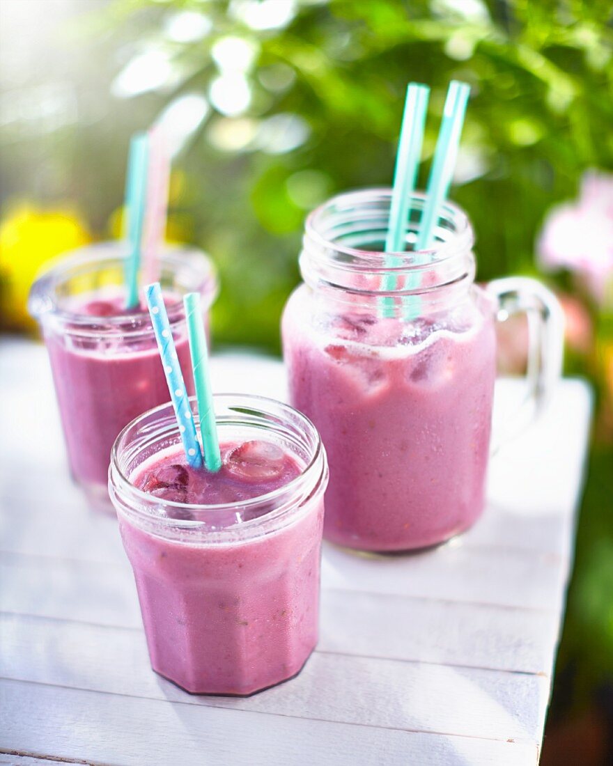 Beeren-Smoothies auf Tisch im Garten