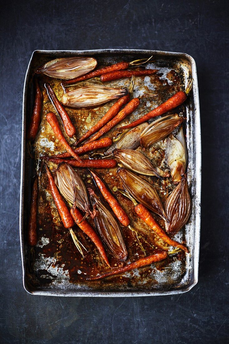 Roasted carrots and shallots on a baking tray