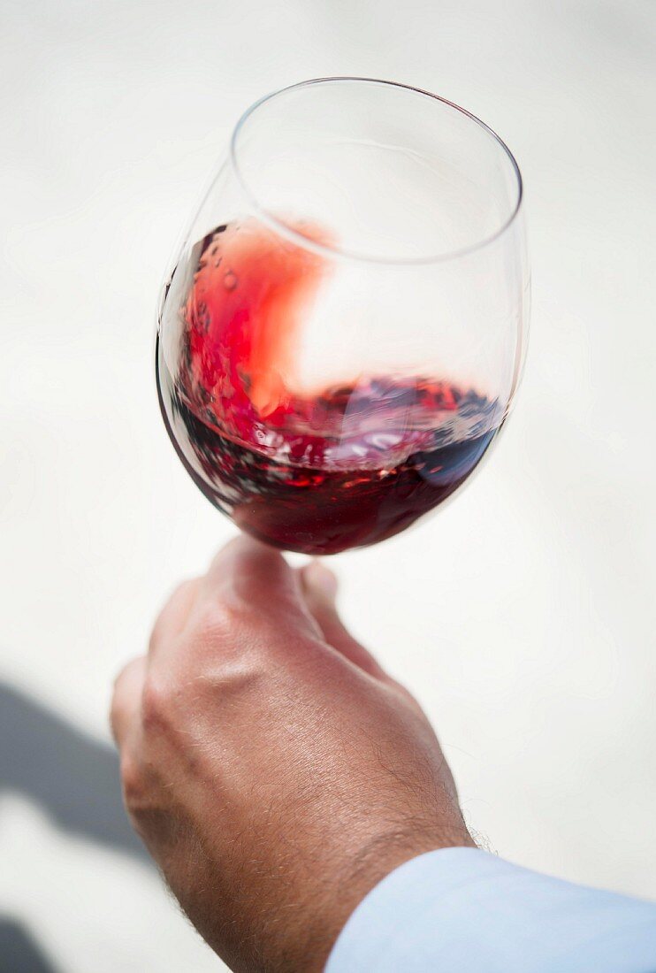 Hand hält Glas mit Rotwein