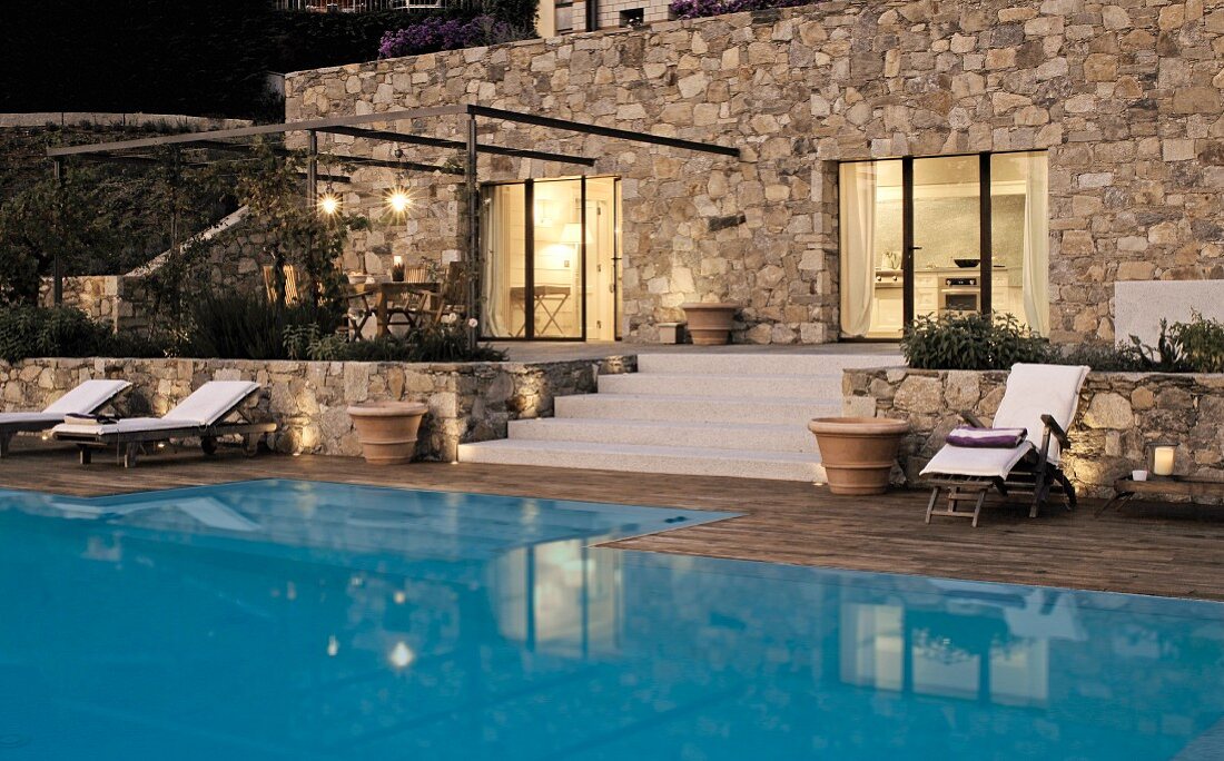 Modern stone house with terrace and pool; twilight atmosphere with candles and lights