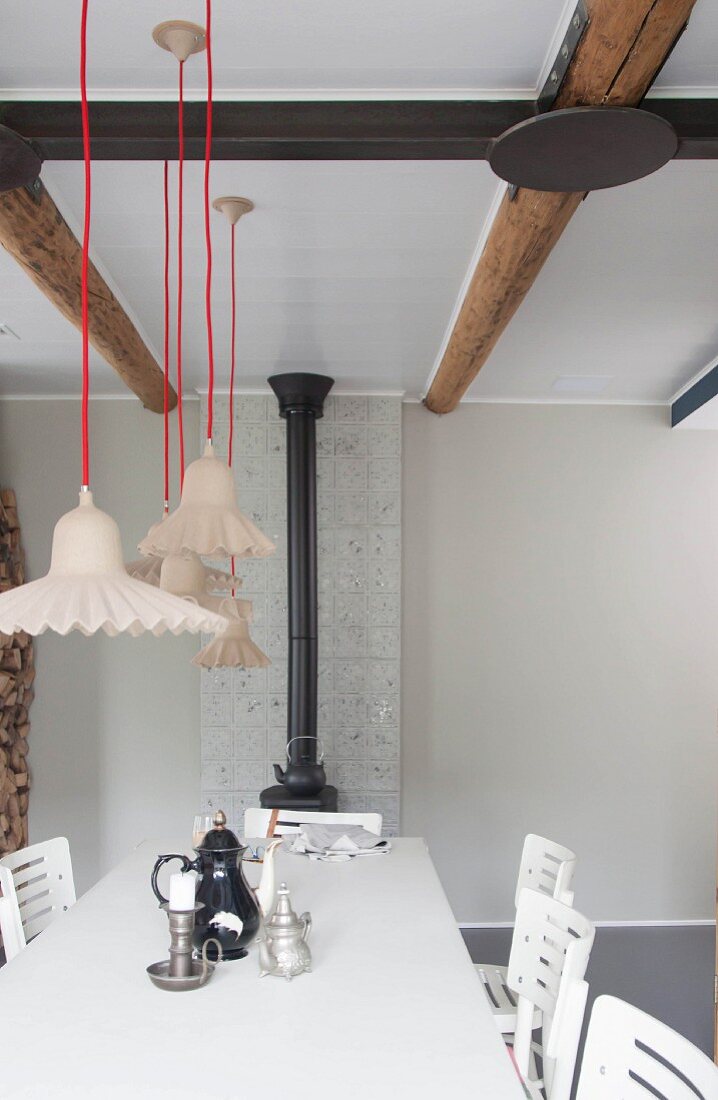 Various pendant lamps suspended from red cords above table