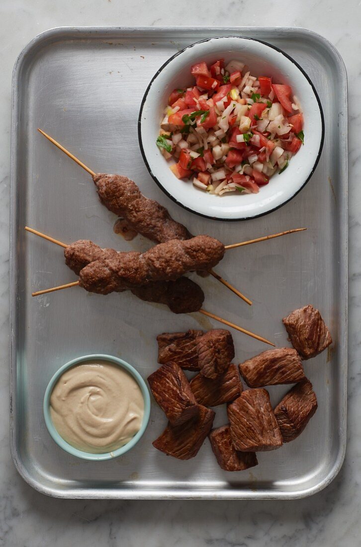 Minced meat kebabs and diced meat with hummus and salsa