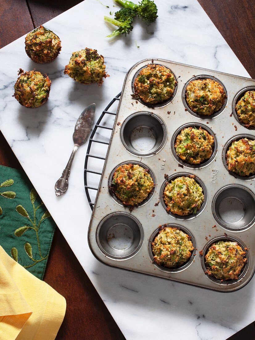 Mini broccoli muffins in a muffin tin on a cooling rack