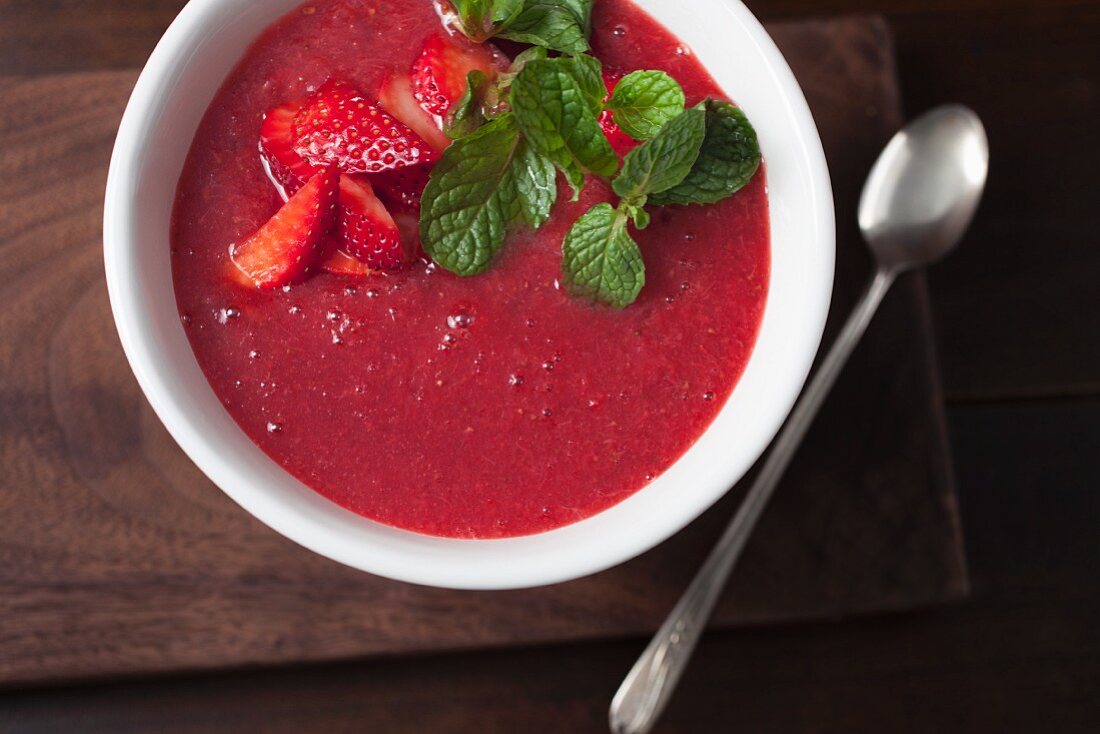 Strawberry sauce with mint in a white bowl on a wooden surface