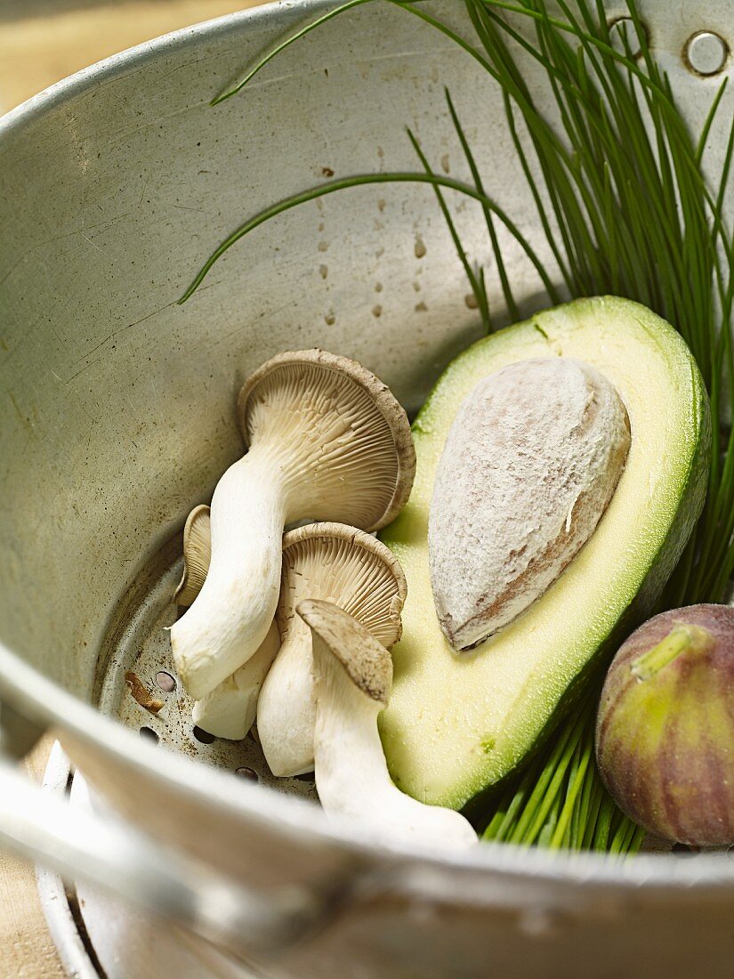 Avocado, mushrooms, figs and chives in a colander