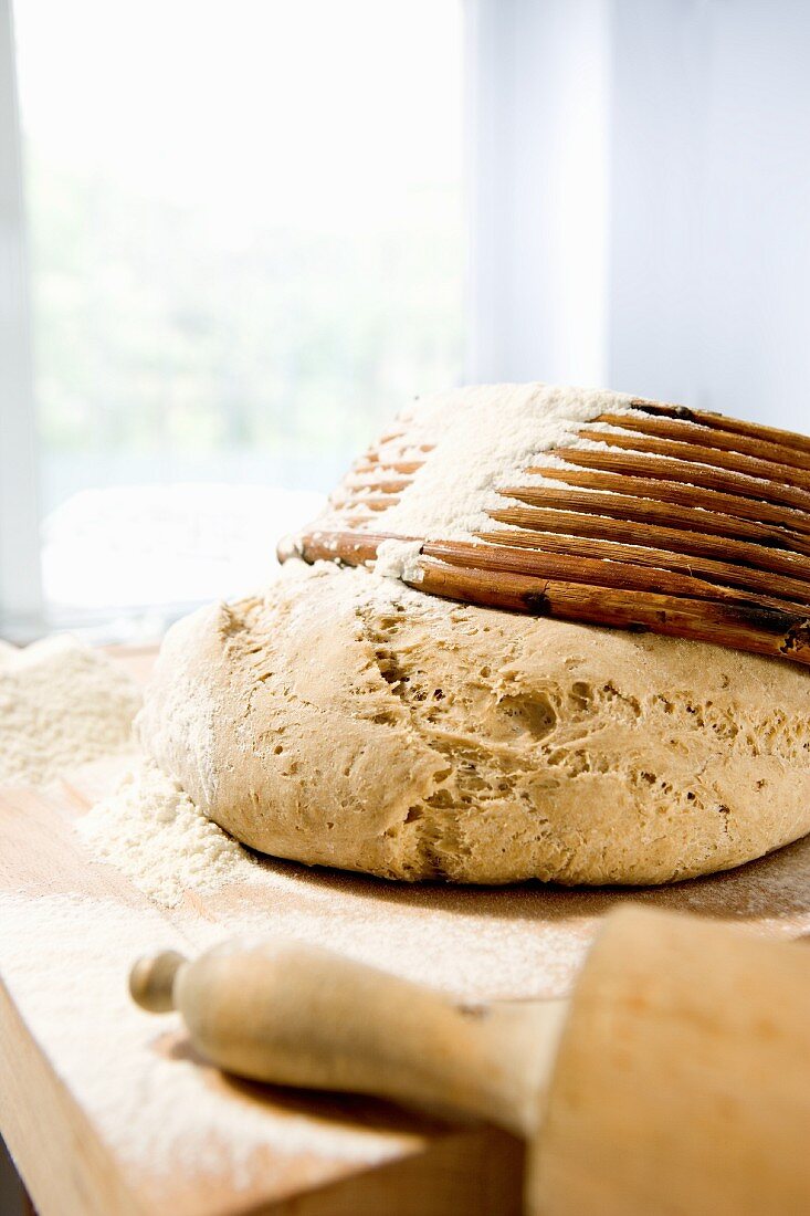 Wheat and rye dough with a baking basket and a rolling pin