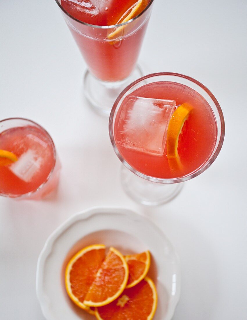 Glasses of blood orange lemonade with citrus slices and ice cubes (seen from above)