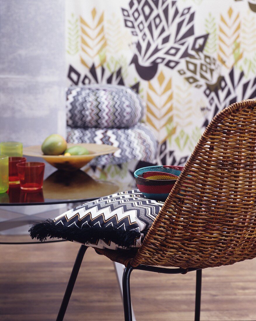 Zigzag-patterned cushion on wicker chair in front of patterned wall