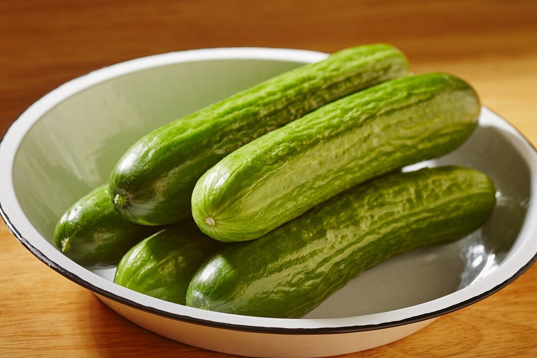 Whole fresh Asian cucumbers in an enamel bowl