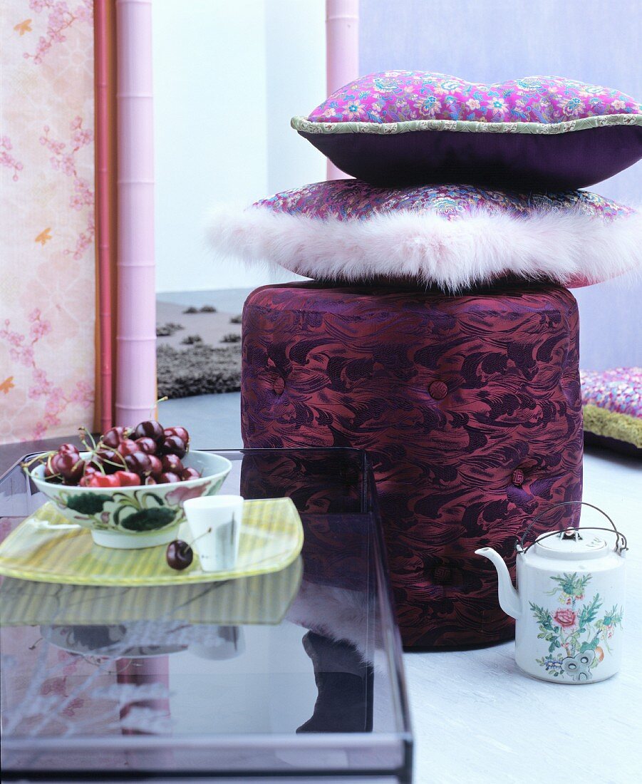 Floral cushions on pouffe behind bowl of cherries
