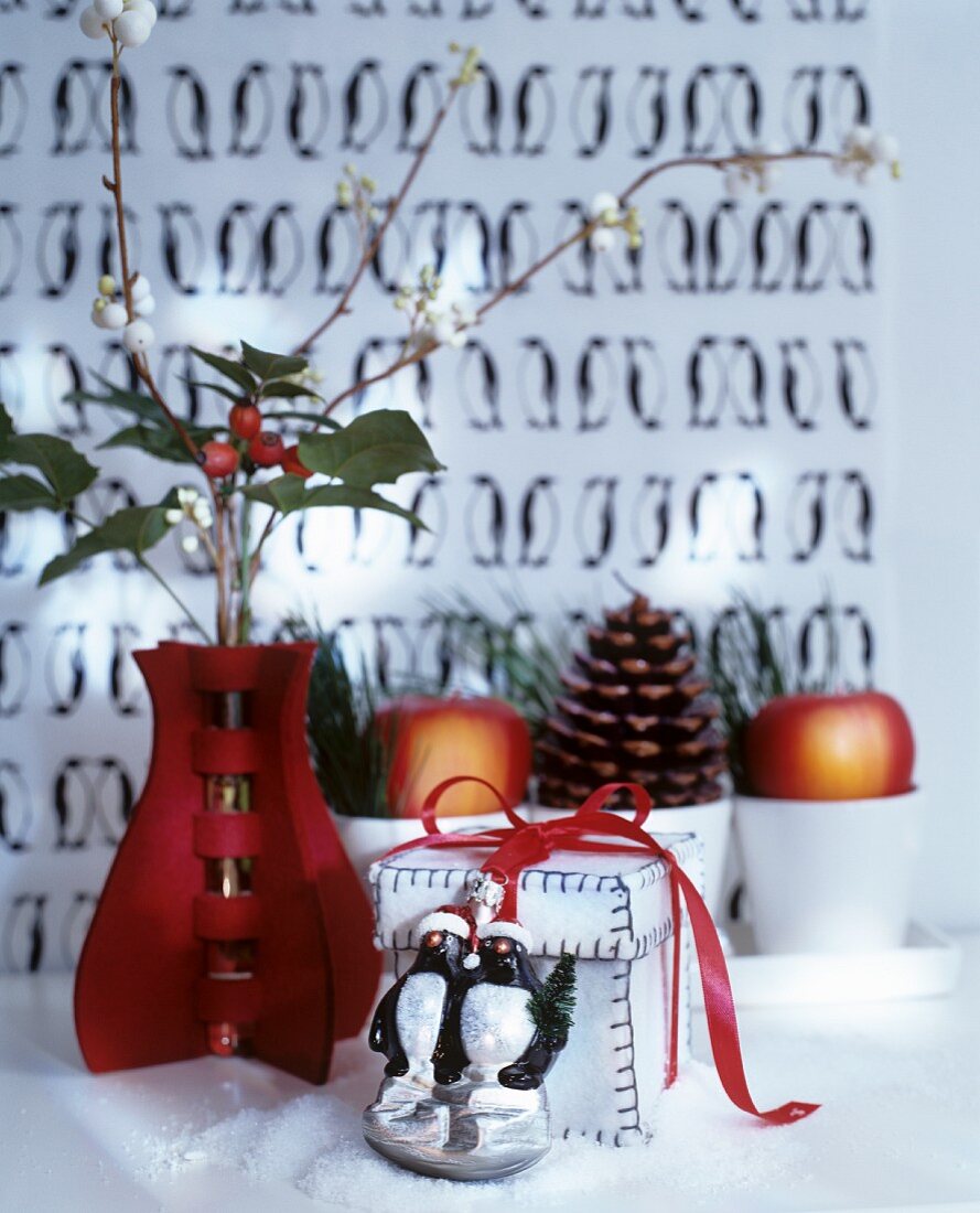 Weihnachtliches Arrangement mit roter Vase, Geschenkschachtel und Deko-Tierfigur