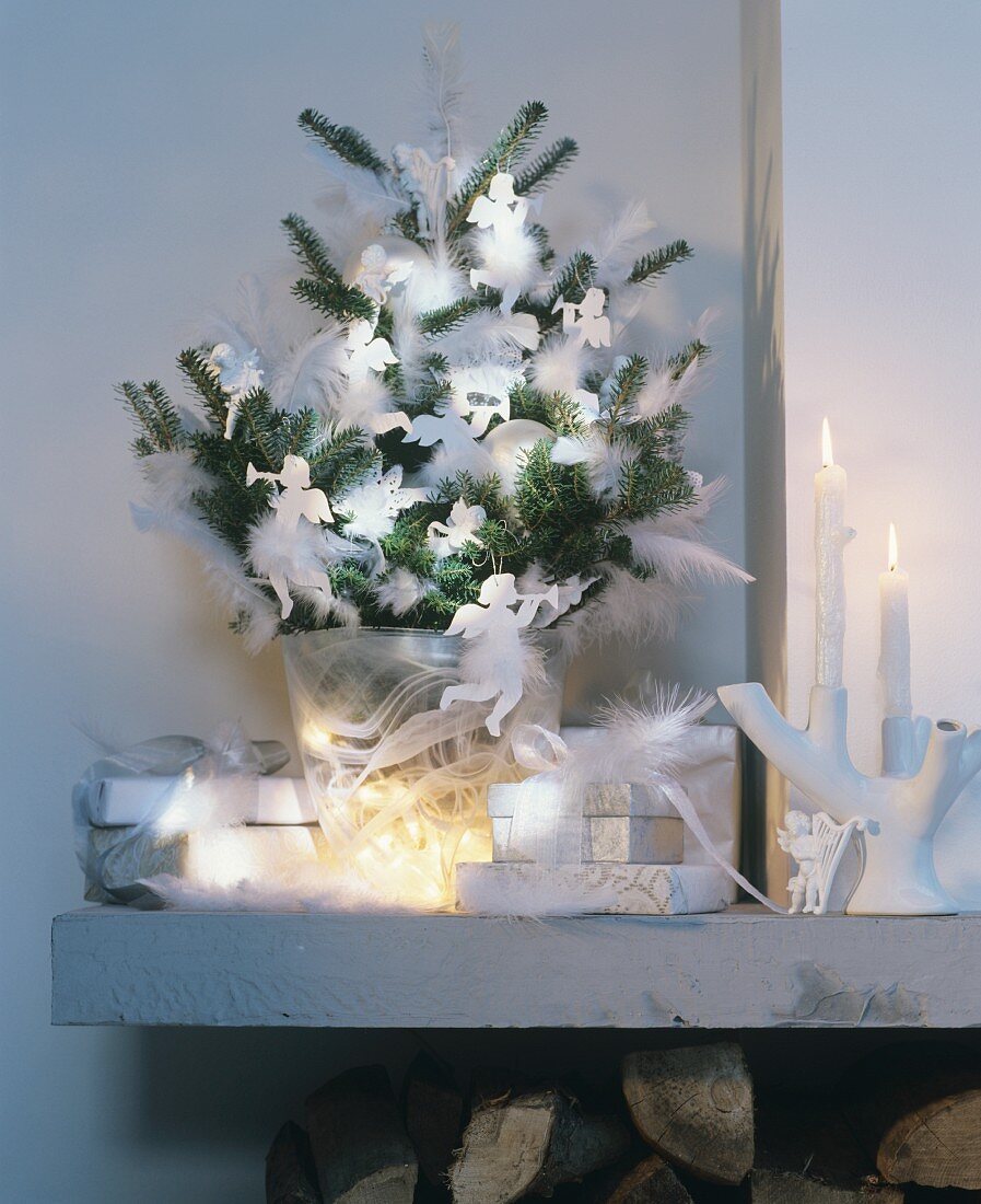 Green fir branches decorated with white feathers and angel ornaments in glass vase