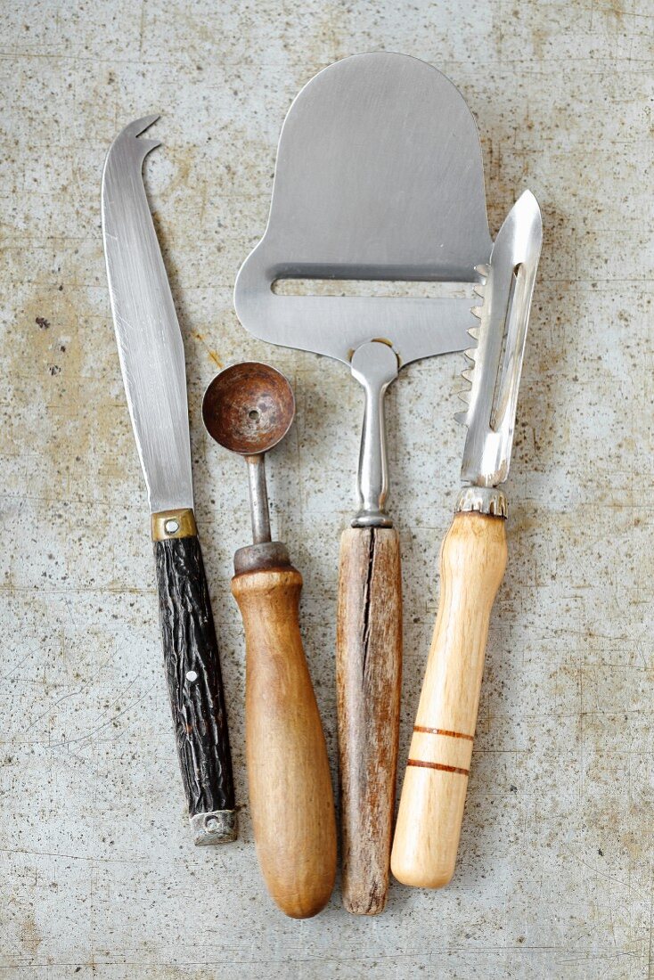 Vintage kitchen utensils: a cheese knife, a melon baller, a cheese cutter and a peeler