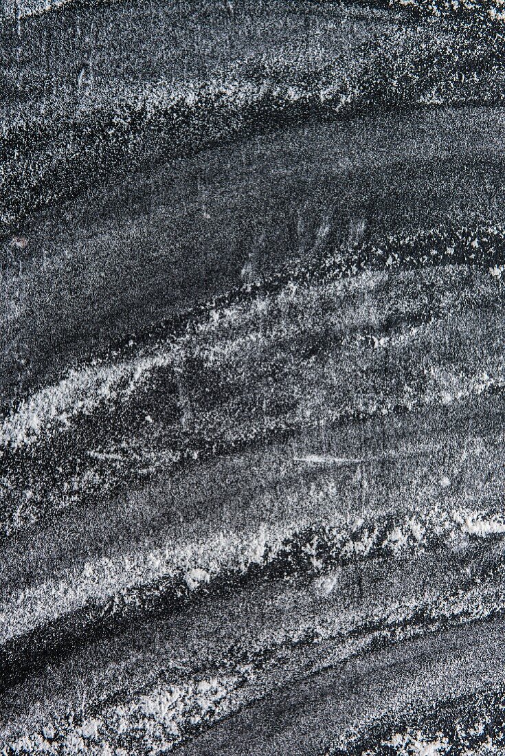 A black surface dusted with flour (seen from above)