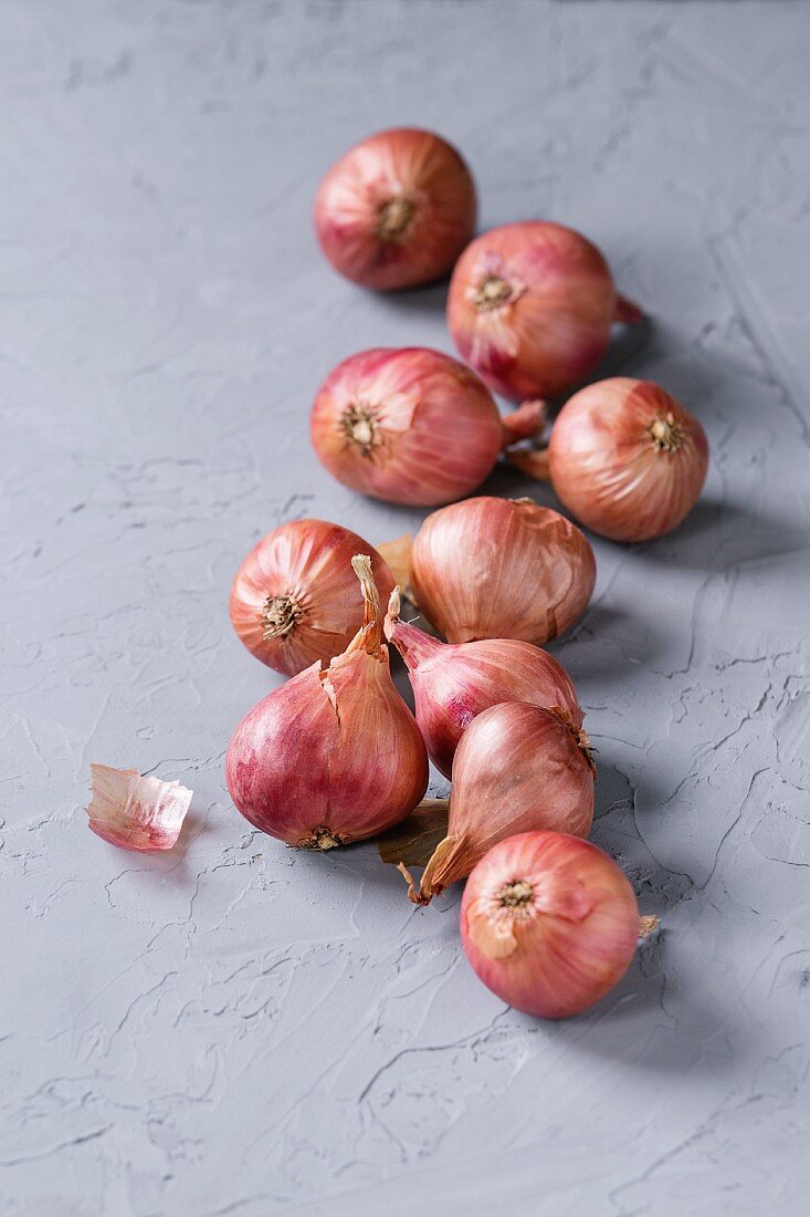 Small red onions on a grey textured surface