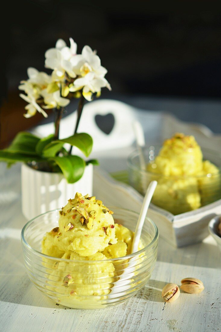 Pistachio ice cream in a glass bowl with flowers in the background