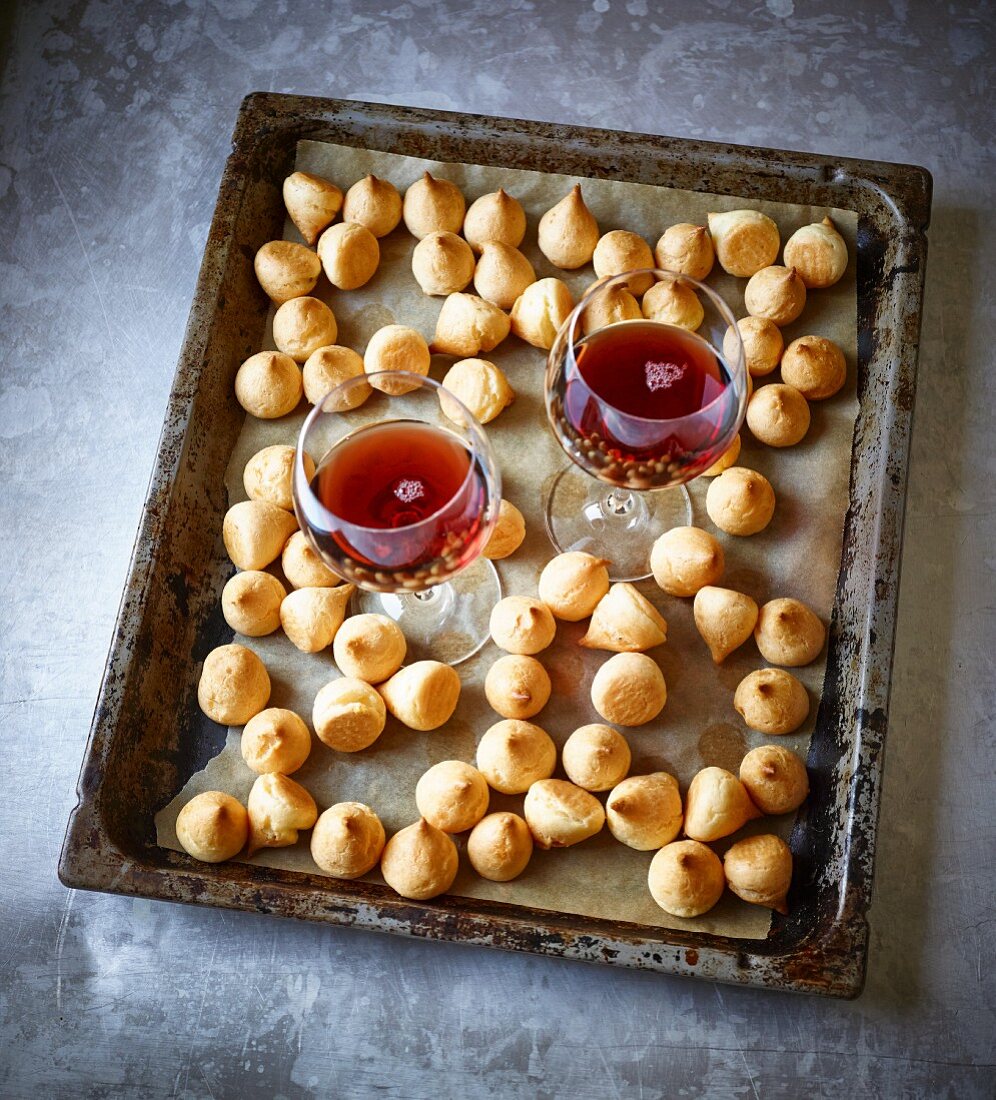 Mini cheese profiteroles on a baking tray with wine
