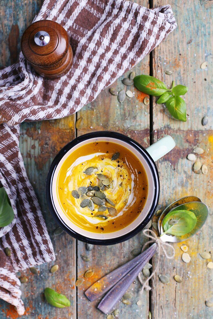 Cream of pumpkin soup with pumpkin seeds on a rustic wooden table