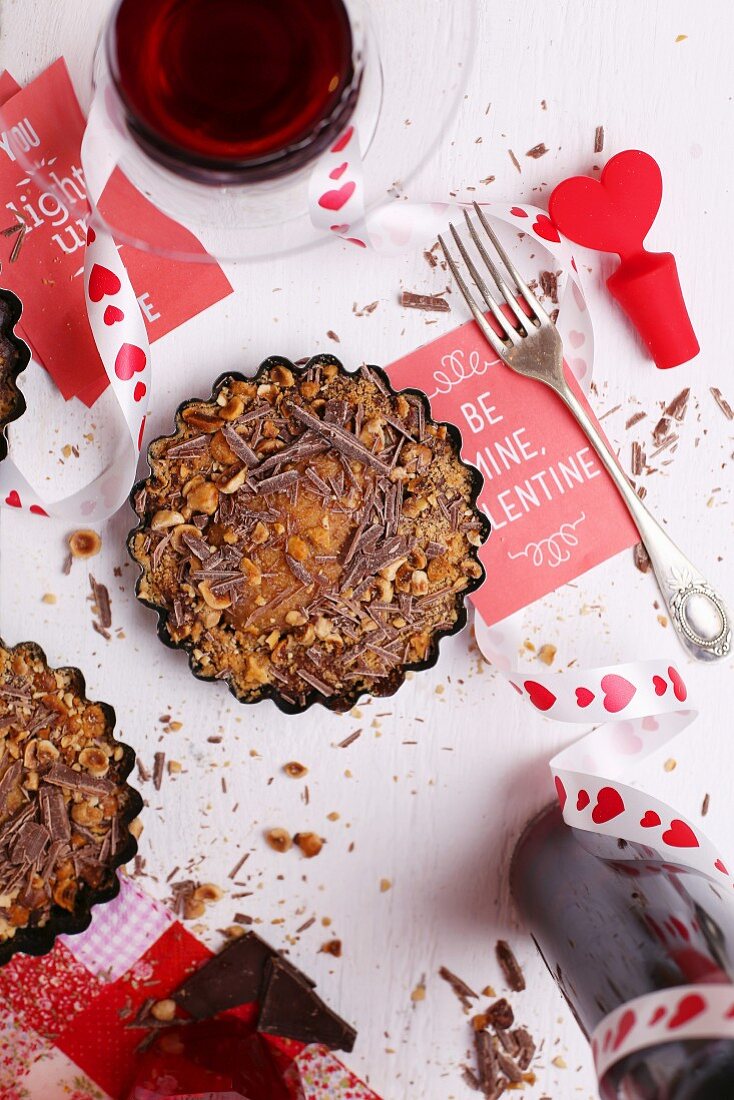 Valentinstags-Dessert mit Rotwein und Deko auf weißem Tisch