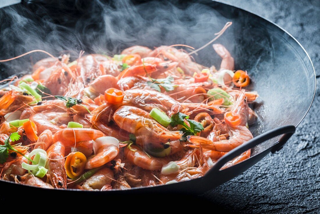 Steaming prawns with garlic, parsley and chilli peppers in a pan