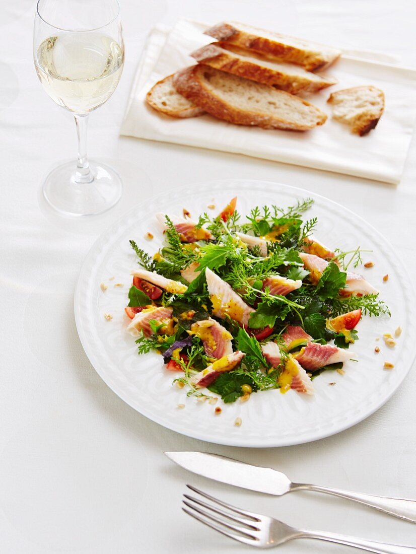Smoked trout with a wild herb salad and bread served with a glass of white wine