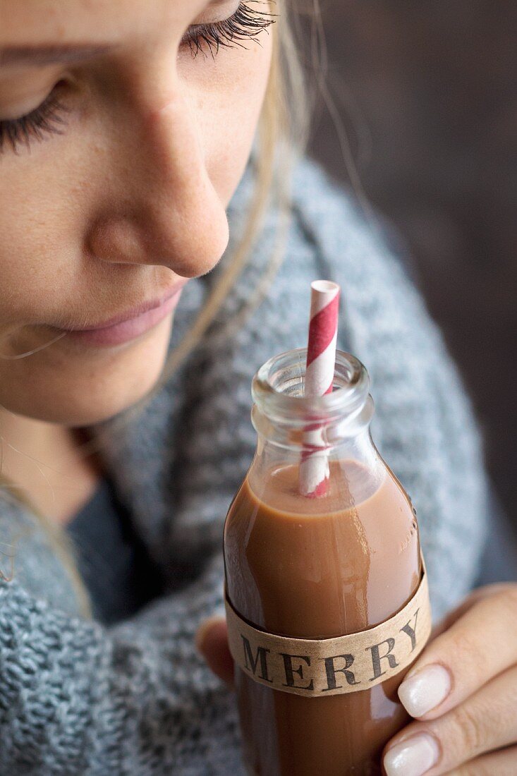 A woman holding a bottle of praline liqueur for Christmas