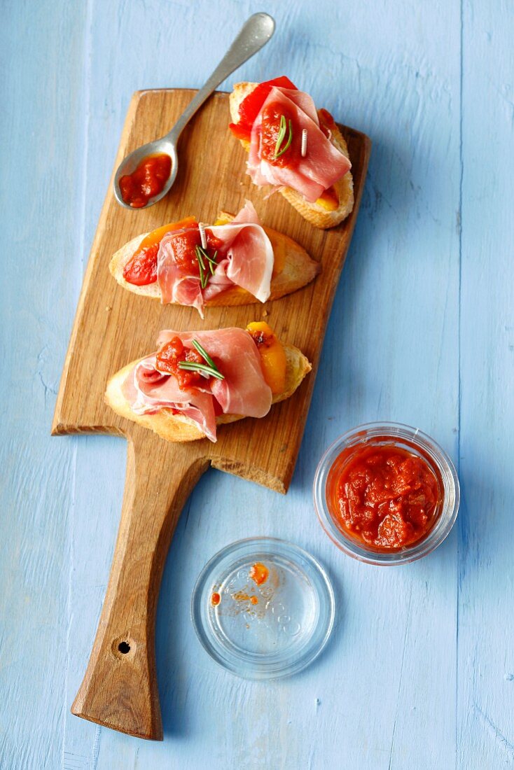 Sliced baguette topped with Serrano ham, grilled peppers and hot tomato salsa