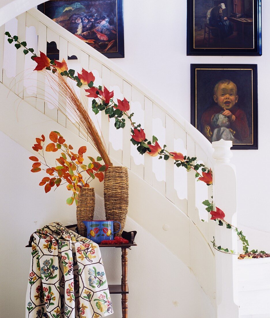 Strand of ivy and red autumn leaves twining up staircase balusters
