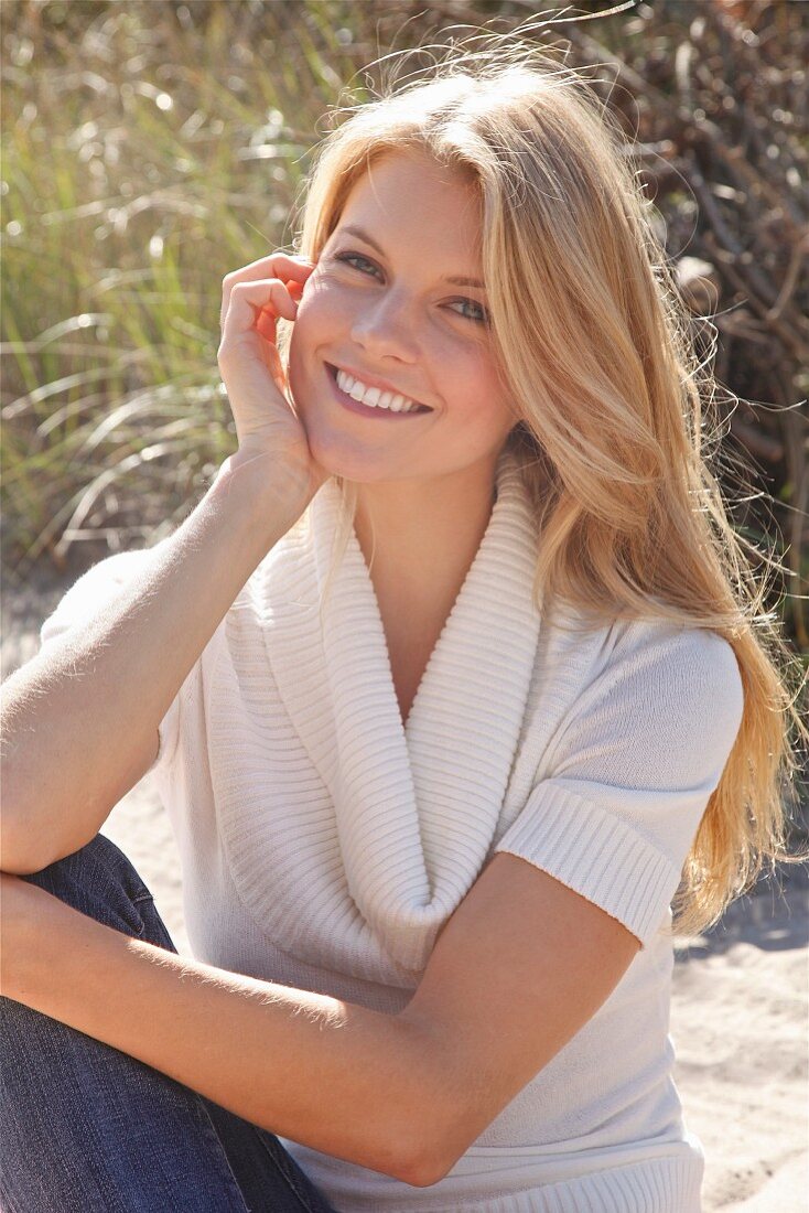 Young blonde woman wearing jeans and knitted top