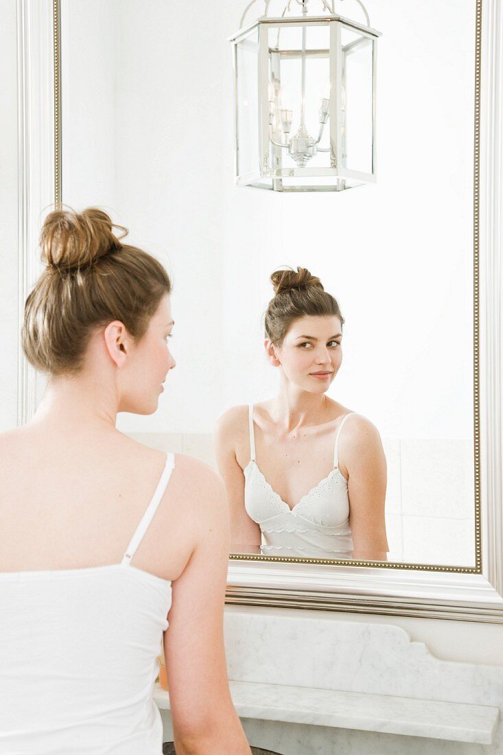 Woman wearing lace camisole looking in mirror