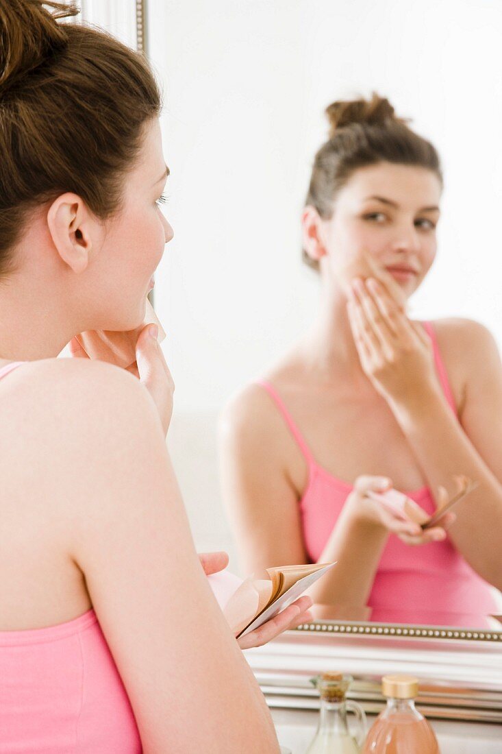 Woman patting powdered paper on face