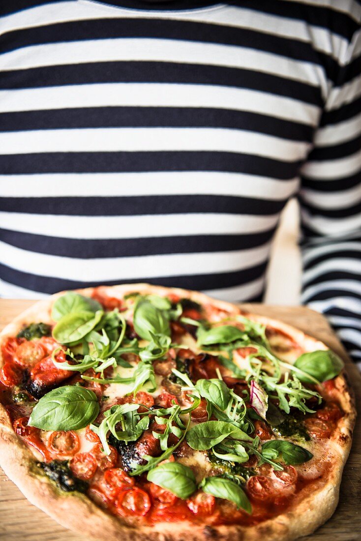 Pizza mit Tomaten, Basilikum und Rucola auf Holzbrett