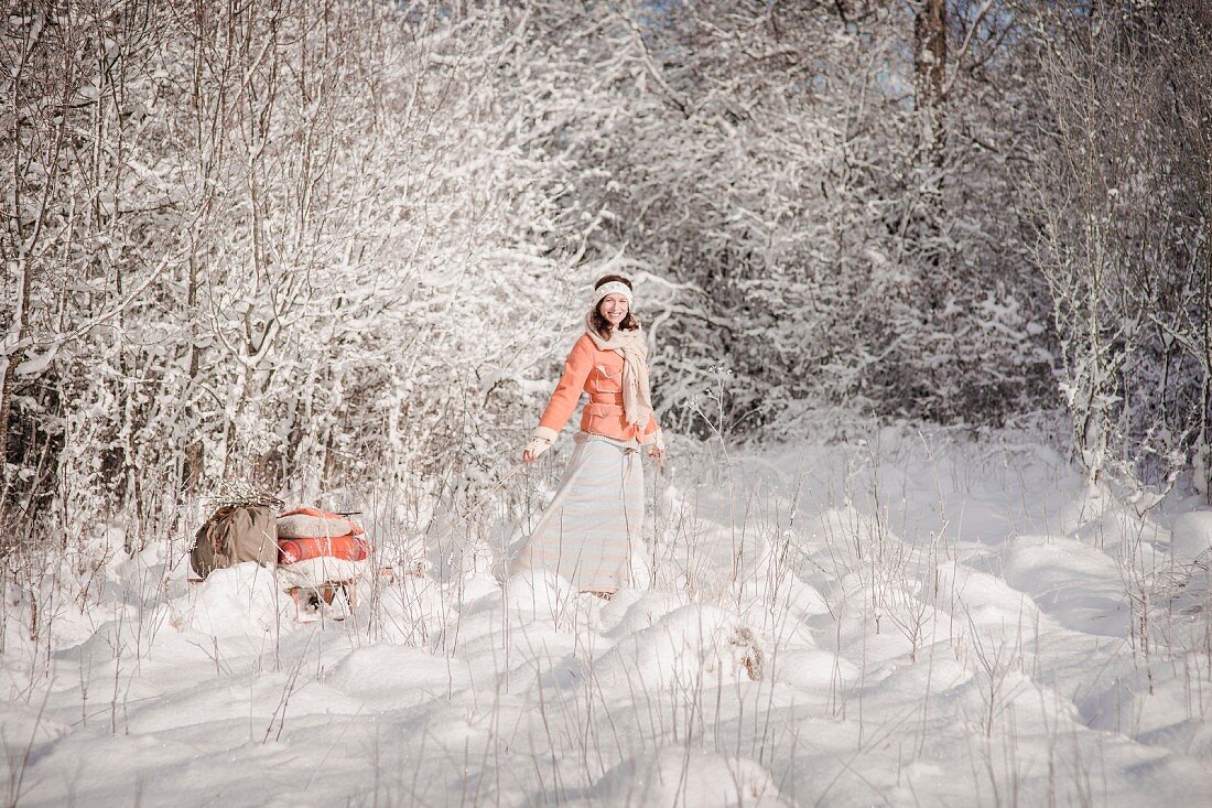 Woman pulling a loaded sledge through a winter landscape