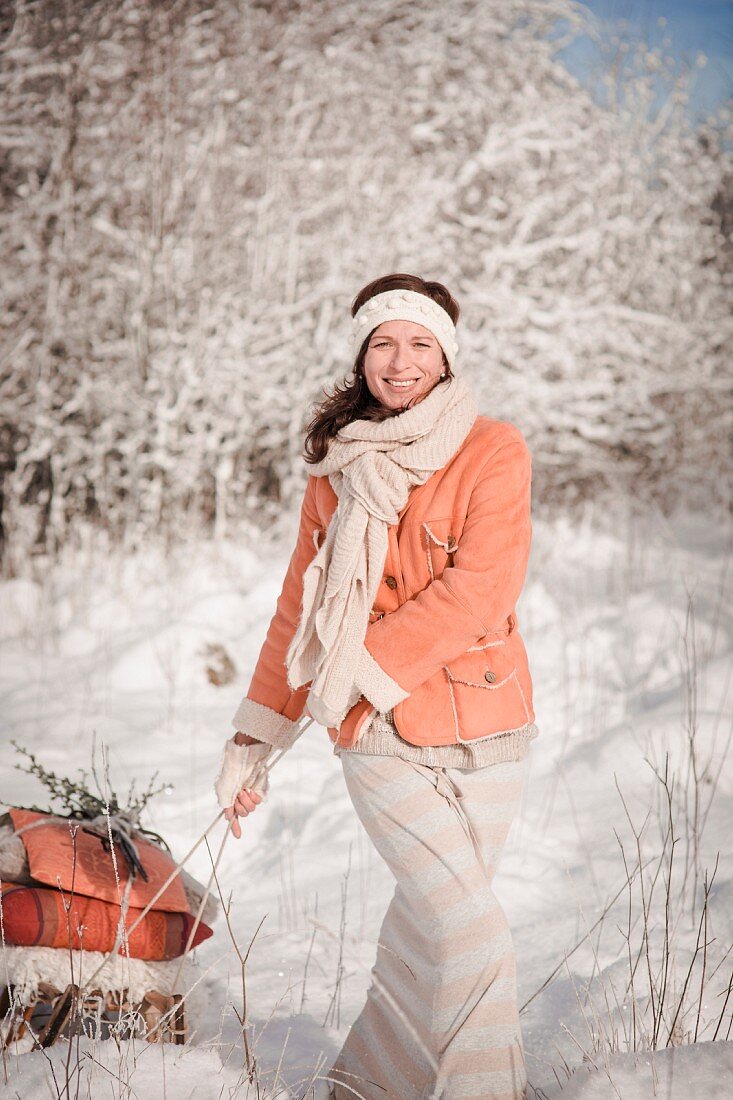 Frau zieht einen bepackten Schlitten durch Winterlandschaft