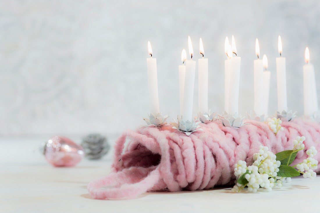 Small lit candles stuck in ball of pink wool