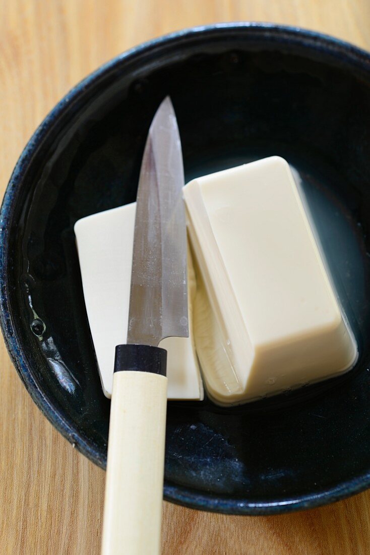 Ein Stück Seitan mit Messer in Keramikschüssel