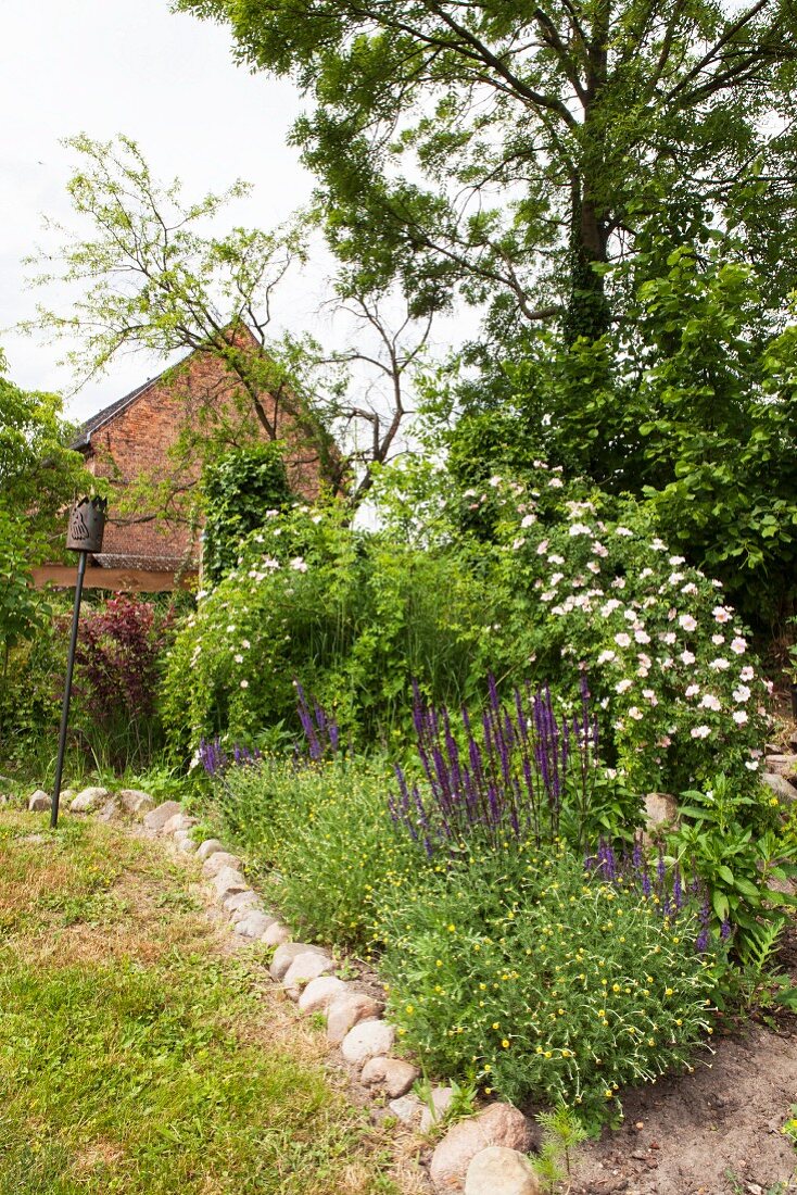 Mit Steinen eingefasstes Beet in naturnahem Garten