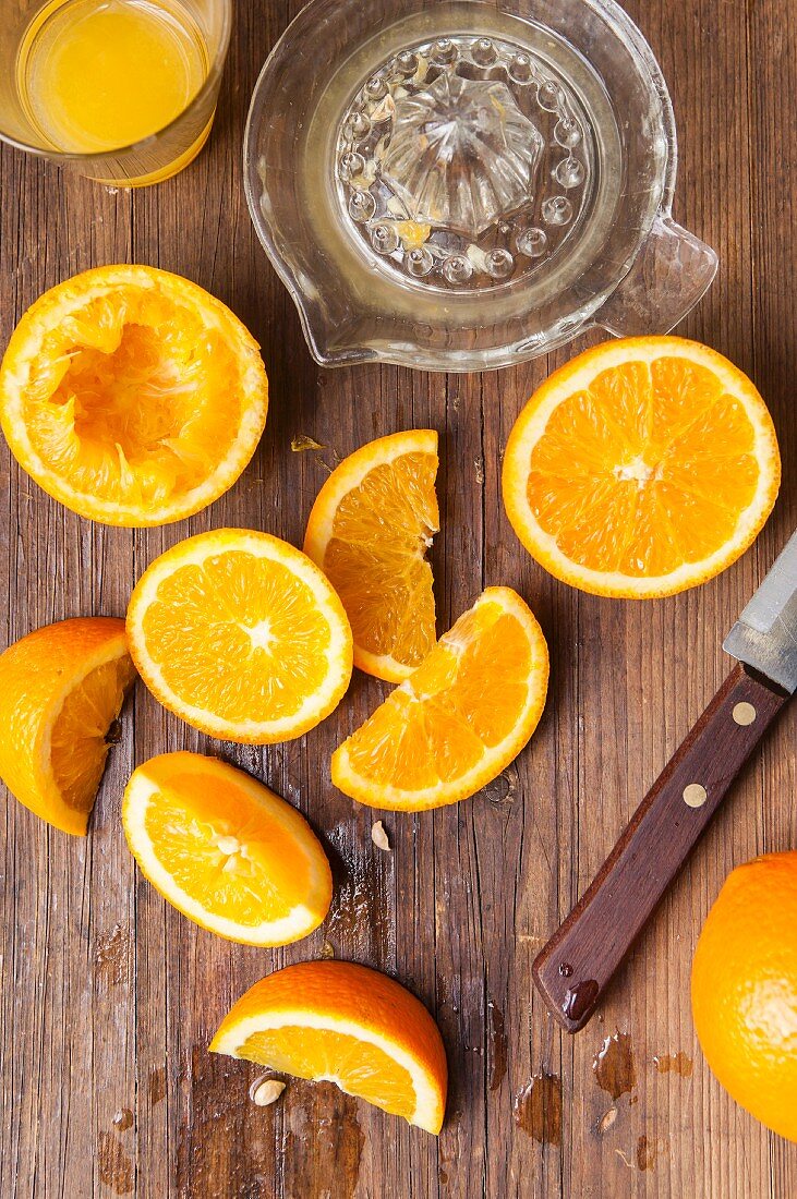 Ein Glas Orangensaft mit Zitruspresse und ausgepressten und geschnittenen Orangen