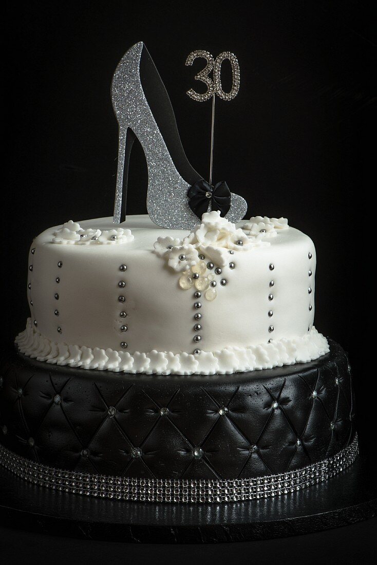 A two tier birthday cake in black and white decorated with a shoe