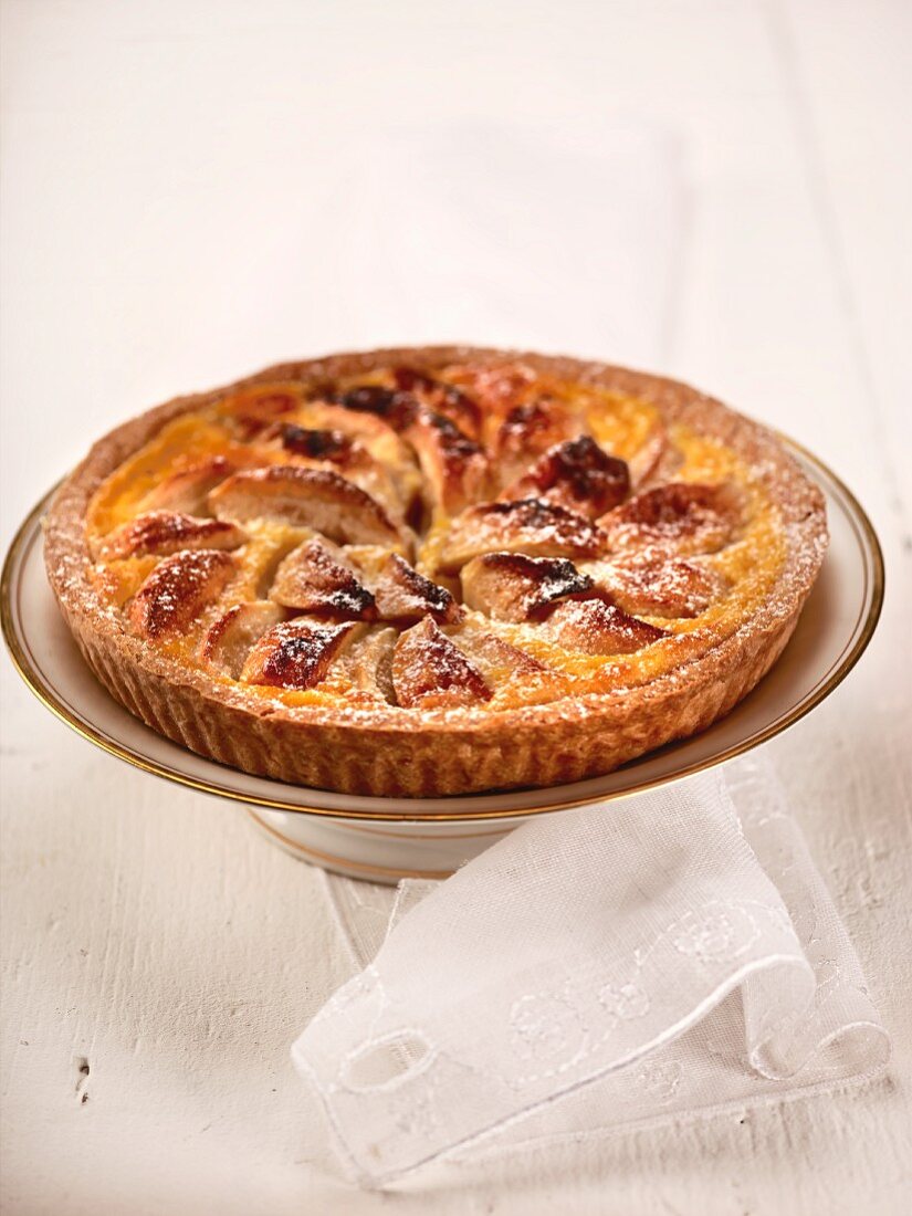 Apple tart with icing sugar on a cake stand