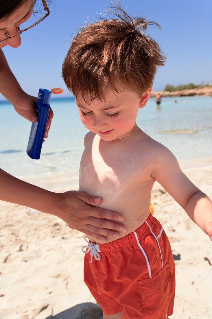 Apply UV sun lotion to small boy