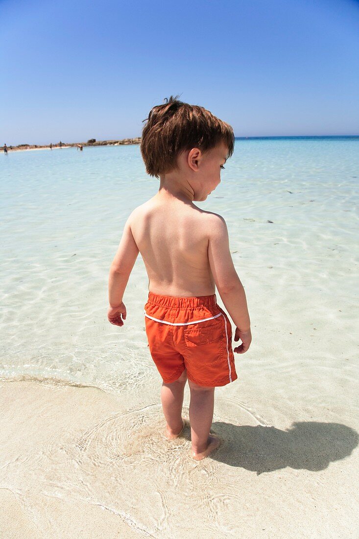 Boy testing the sea temperature with feet