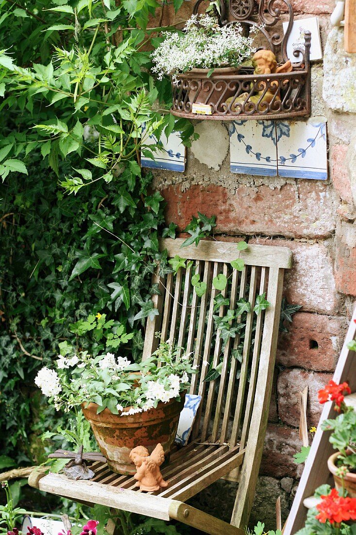 Hölzerner Gartenstuhl als Ablage für blühenden Terrakottatopf