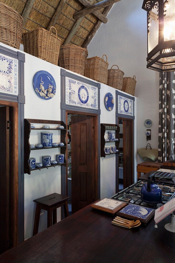 Kitchen counter in front of low installation with doors decorated with blue and white tiles and row of baskets on top